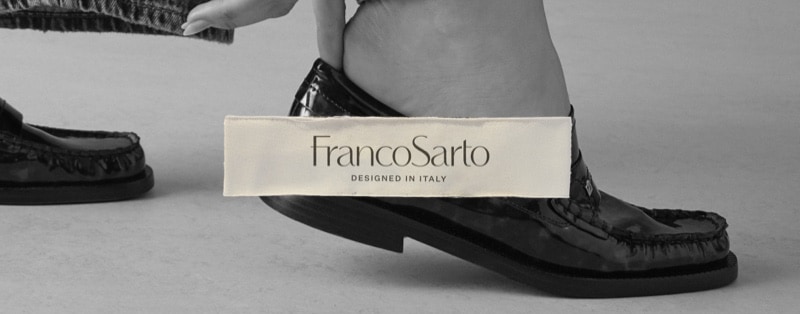 A woman slipping on a pair of tortoise-print patent leather loafers. The Franco Sarto logo is overlaid.