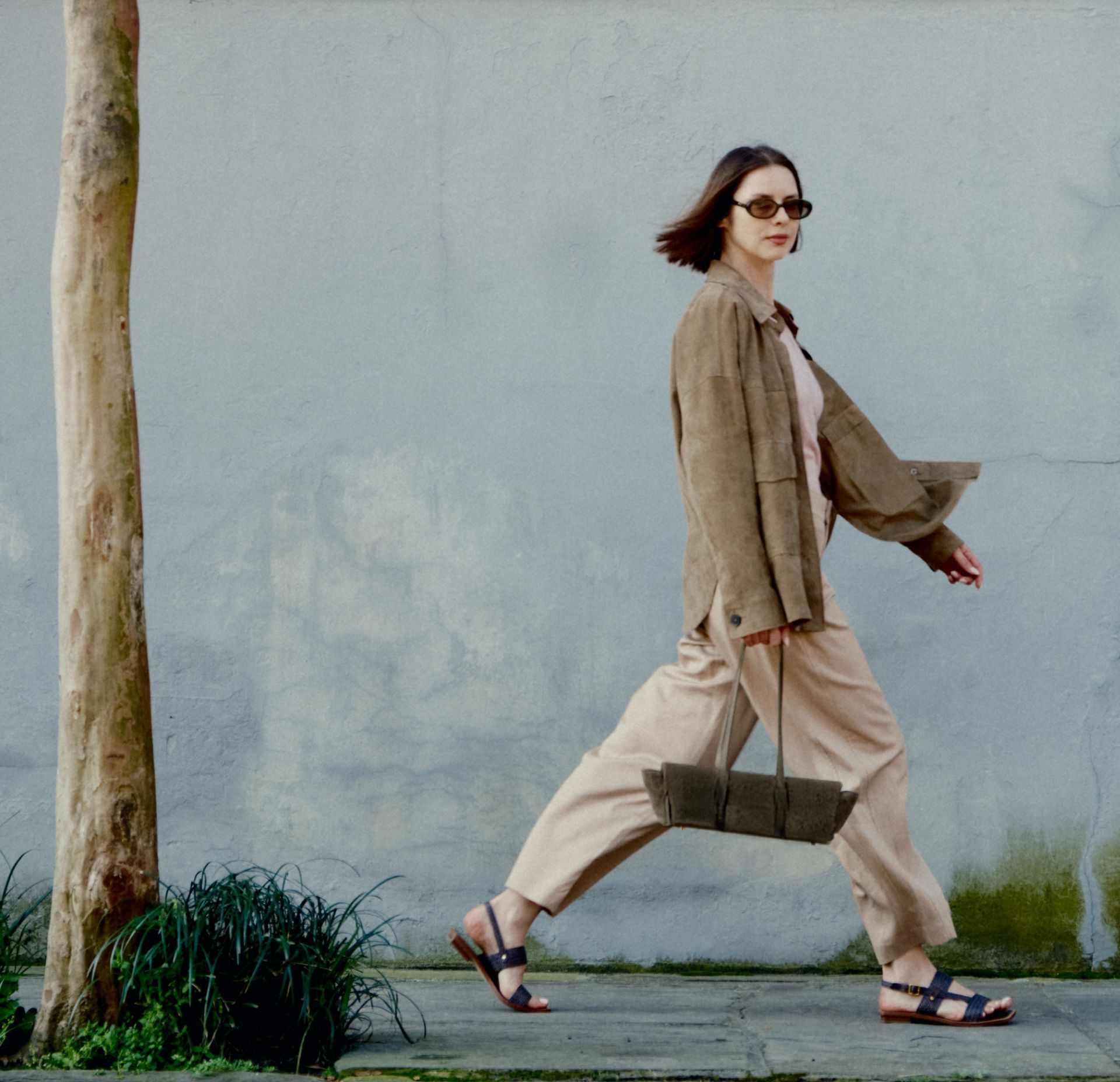 Woman walking outdoors wearing nany Franco Sarto Enrica Sandals with wide-leg trousers and a brown suede jacket