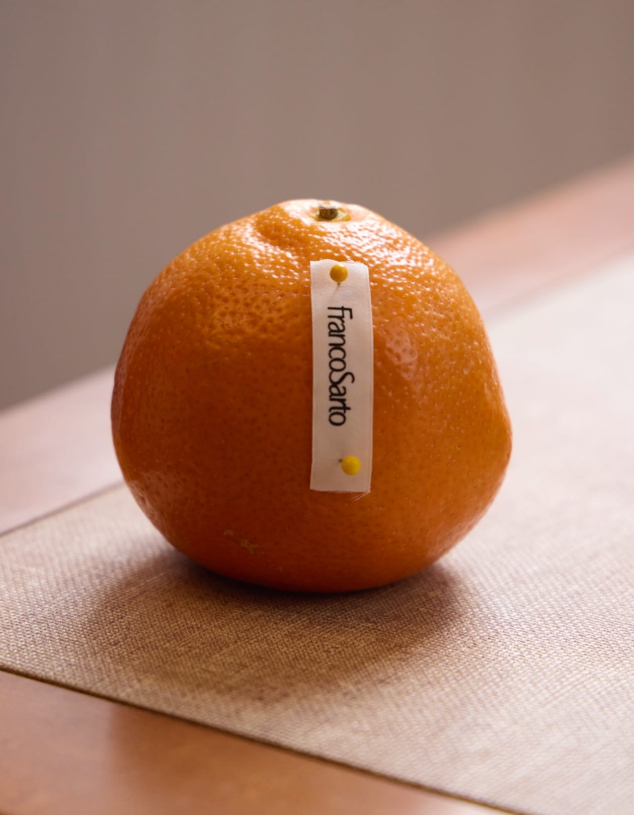 an orange with a franco sarto shoe tag pinned to it