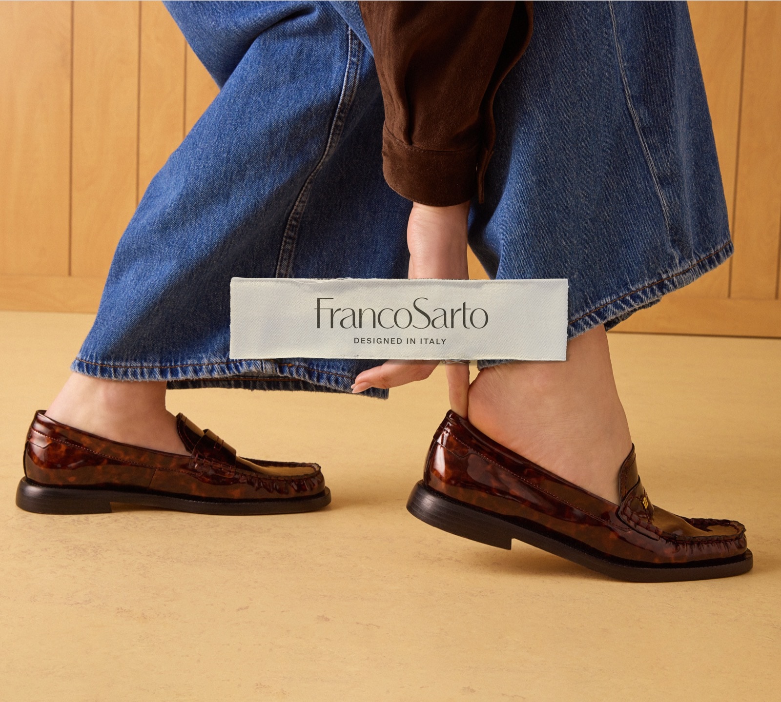 A woman slipping on a pair of tortoise-print patent leather loafers. The Franco Sarto logo is overlaid.