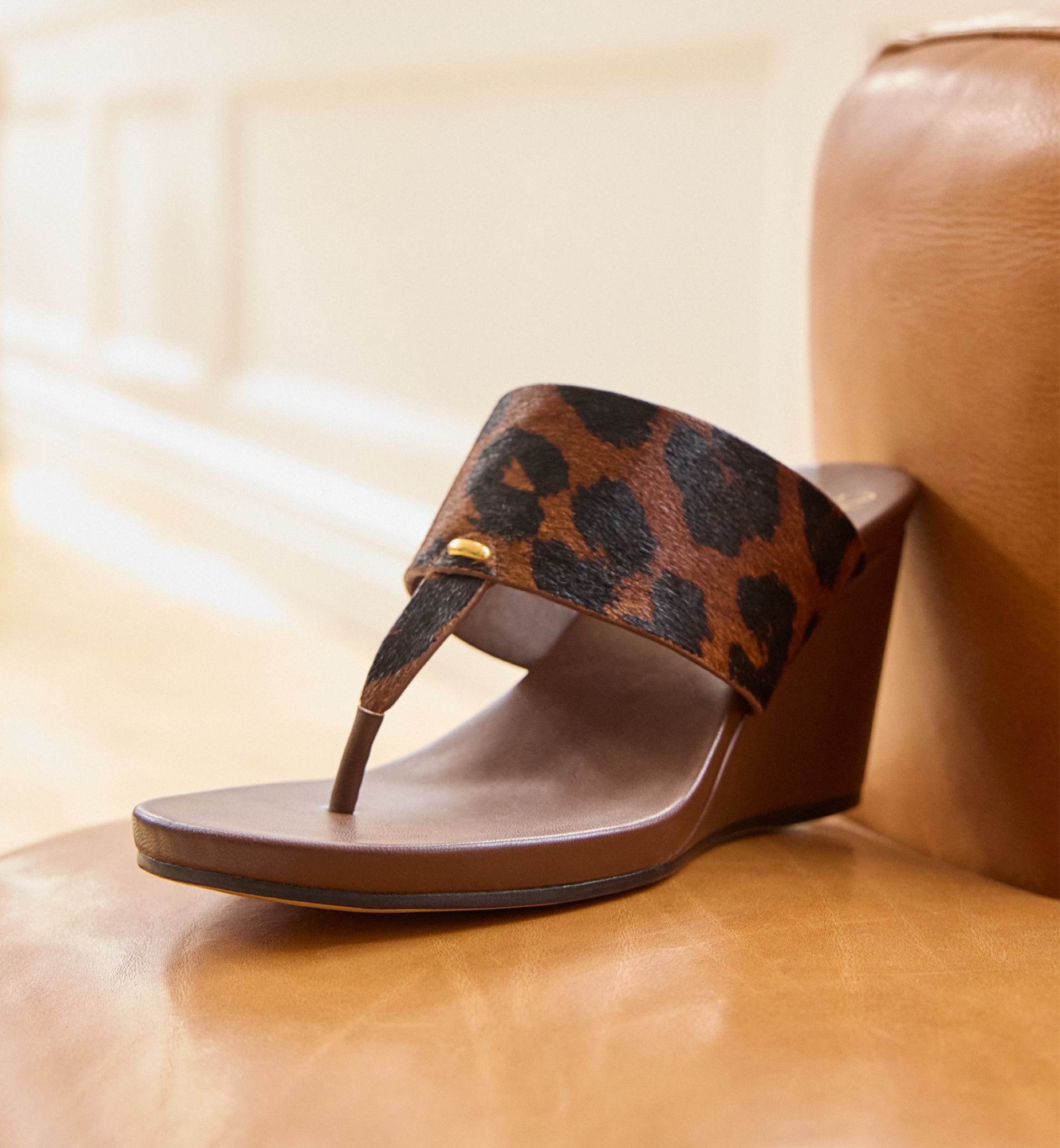 Talea wedge sandal in brown leopard print on a leather chair